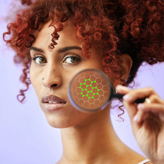 Femme avec loupe devant la joue, visuel du microbiome cutané pour article sur les prébiotiques et l’équilibre de la peau