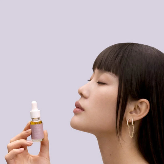 Femme tenant un flacon d’huile visage au CBD, visuel cosmétique pour article sur le CBD en soin visage