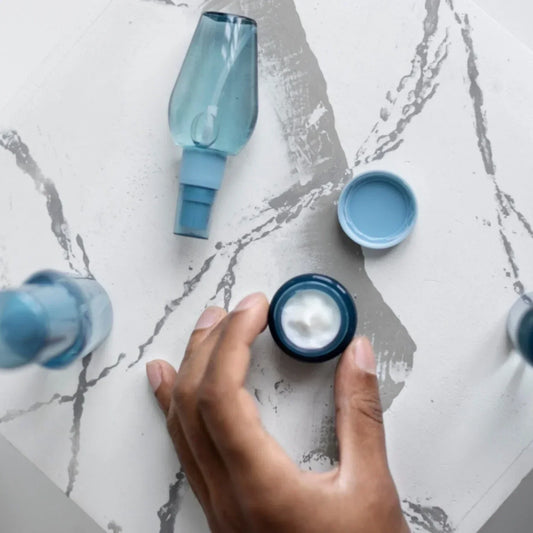 Main tenant un pot de crème hydratante, routine 3 produits pour stabiliser et tester une routine de soin visage.