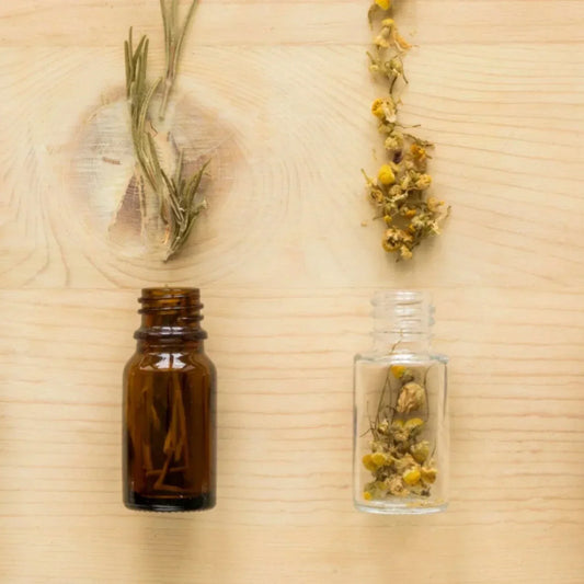 Flacons en verre et plantes séchées sur fond bois, visuel parfum, huiles essentielles et allergènes en cosmétique.