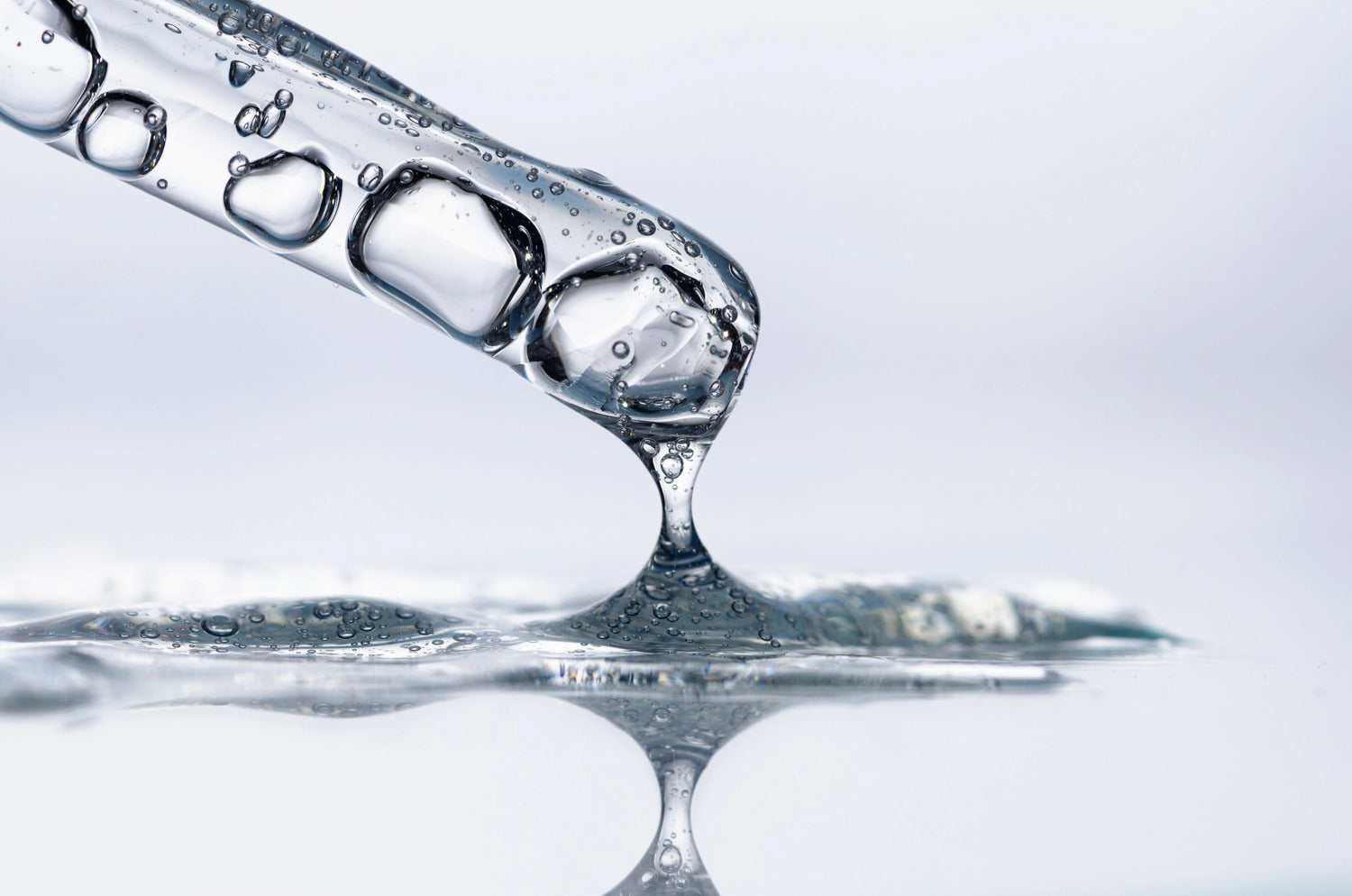 Goutte de sérum transparent au bout d’une pipette, texture type gel pour exfoliation du visage (AHA / acide glycolique).