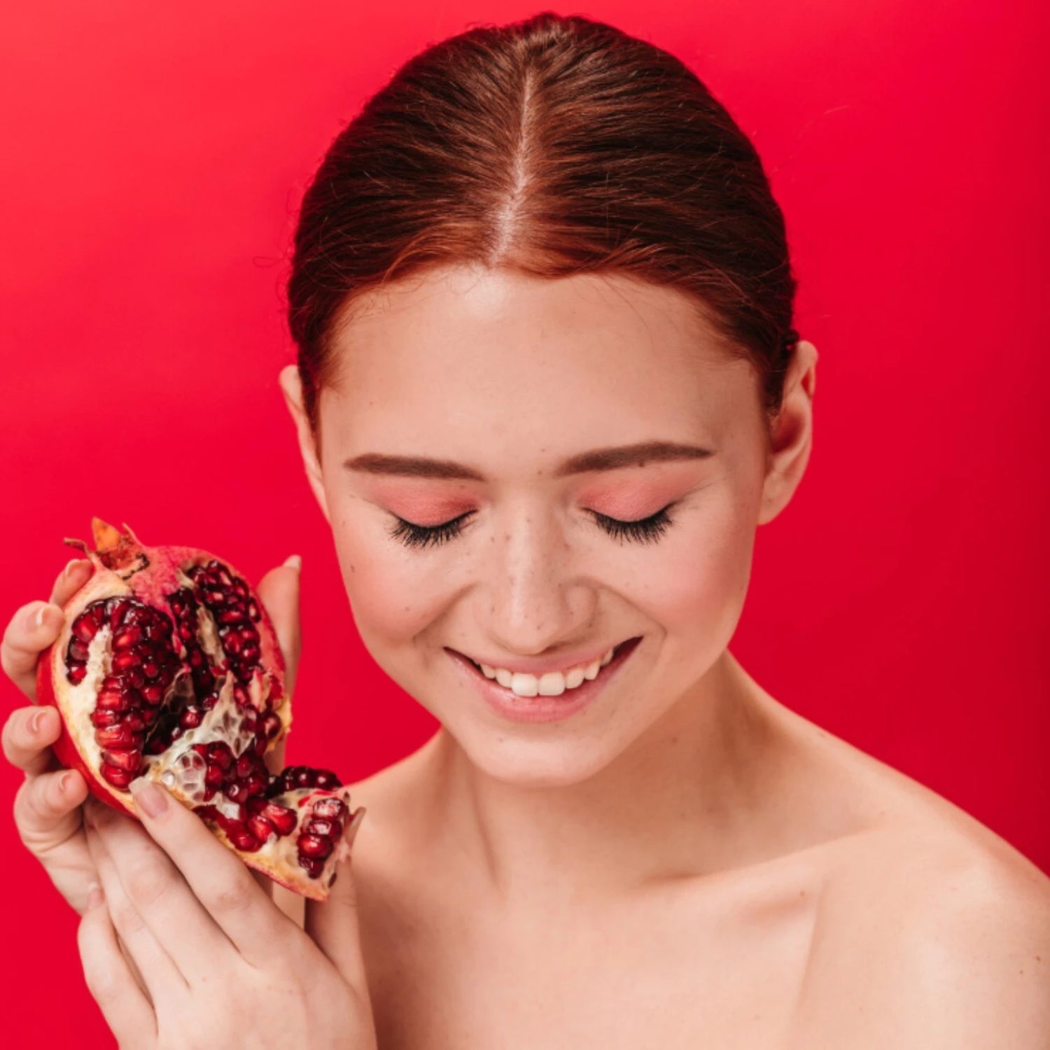 Femme souriante avec un fruit, illustration antioxydants pour la peau et éclat du teint face à la pollution.