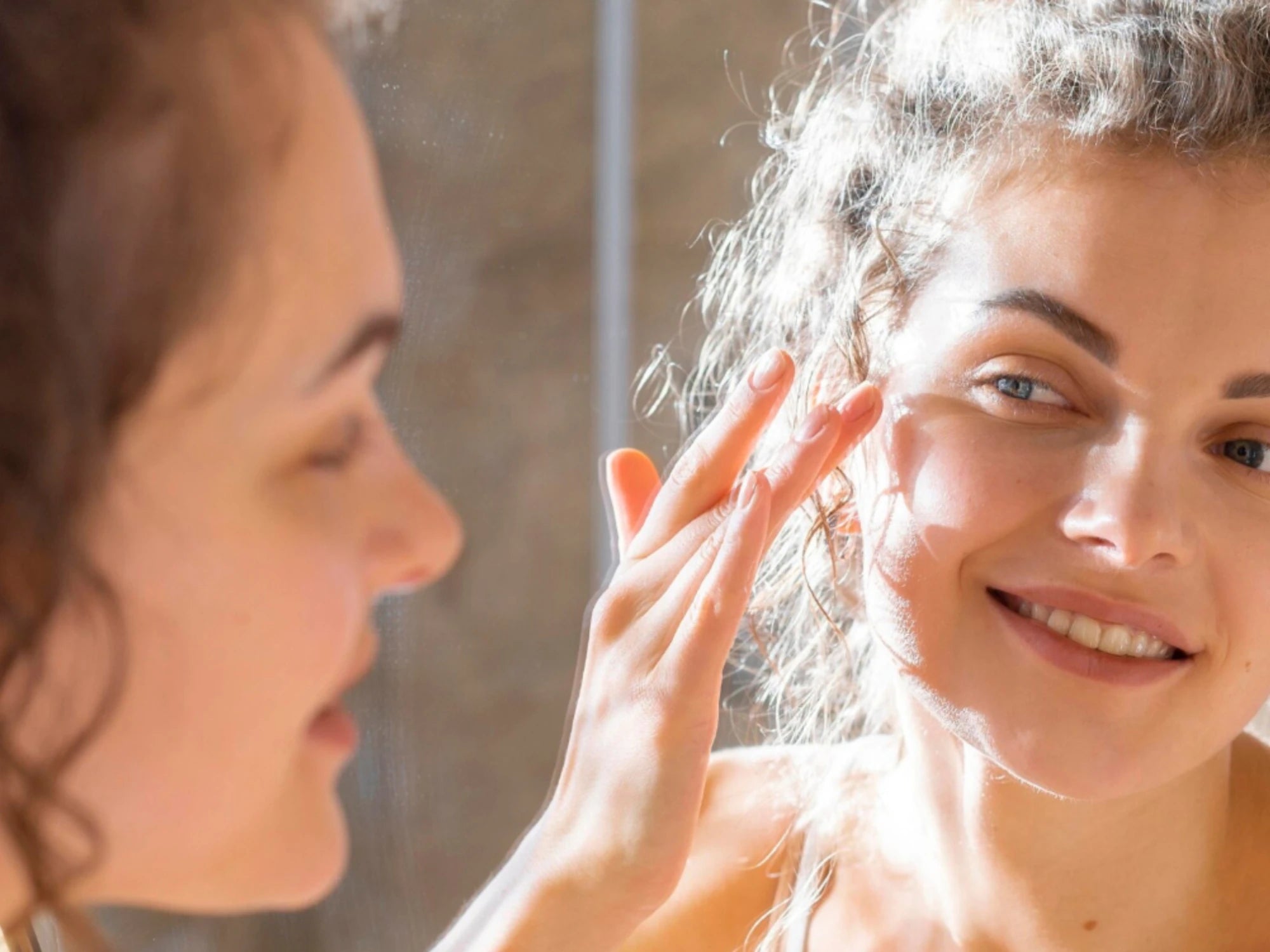 Femme appliquant un soin visage devant un miroir, routine peau grasse avec niacinamide.