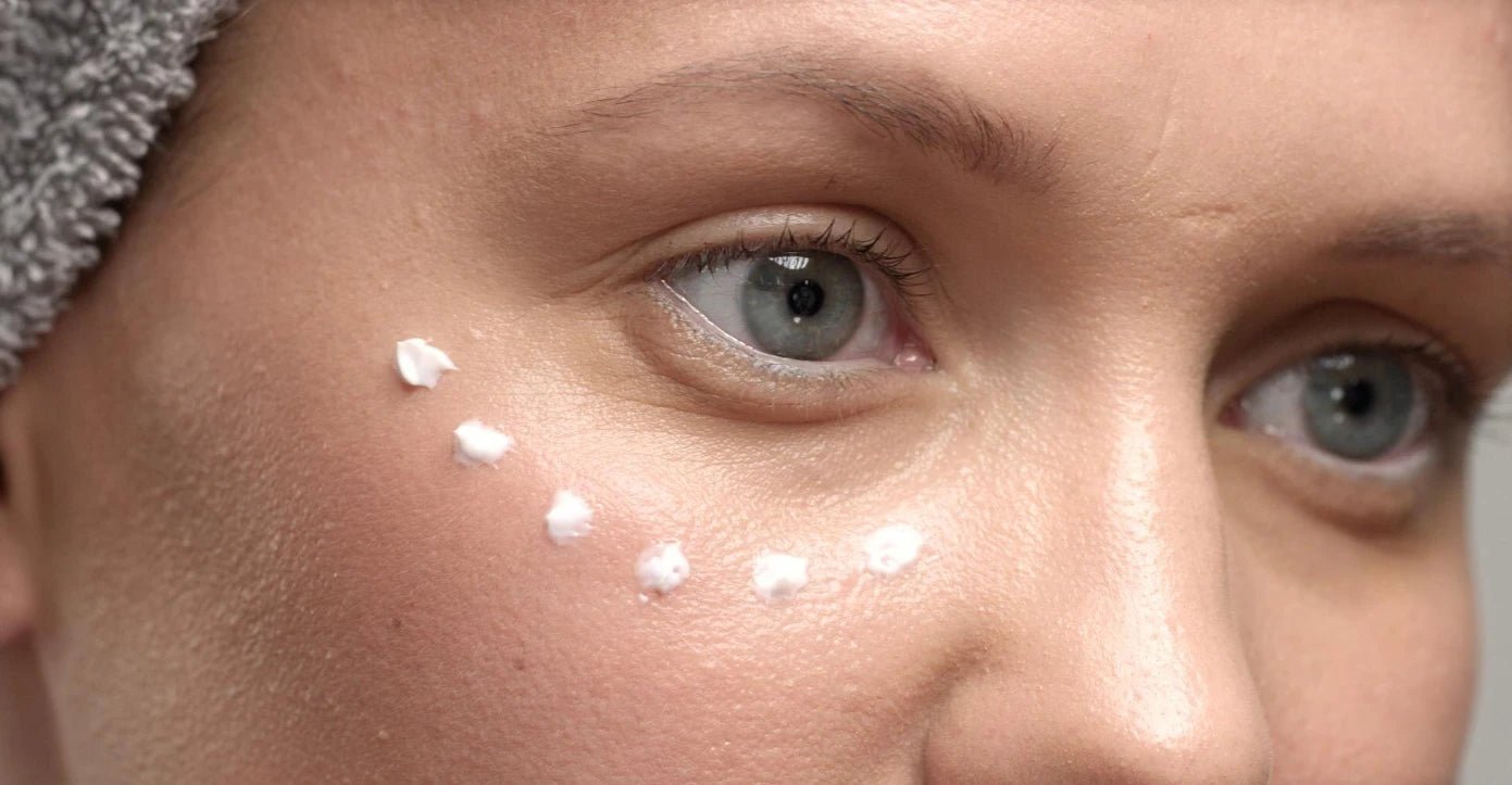 Gros plan sur le contour des yeux avec application de crème, poches sous les yeux.