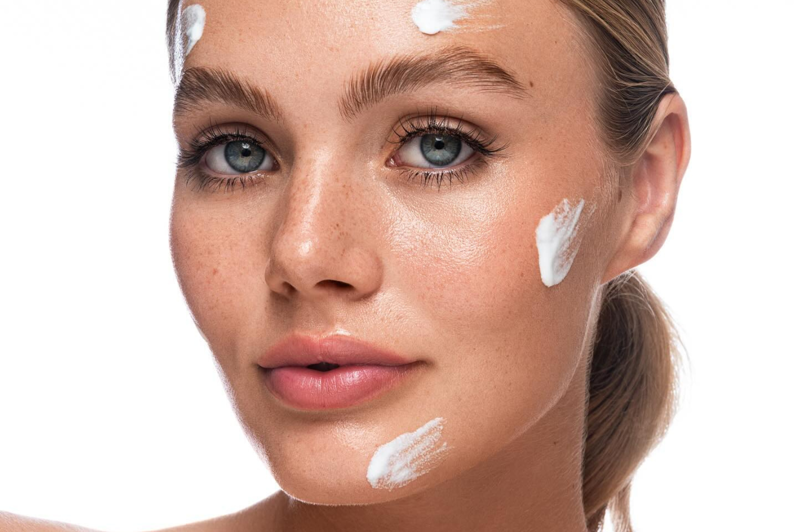 Application d’une crème hydratante sur le visage, texture crème, soin visage pour peau sensible.