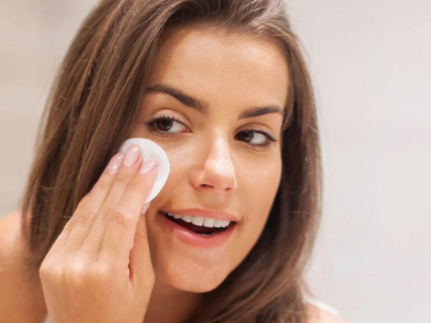 Application du démaquillant biphasé sur le visage avec coton démaquillant