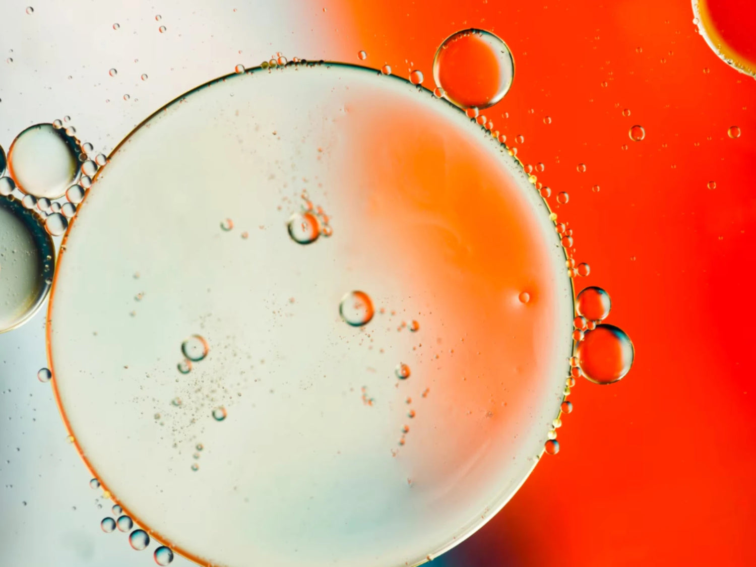 Illustration macro de bulles et phase aqueuse orangée, associée à l’acide lactique (AHA), un exfoliant doux utilisé en cosmétique pour lisser le grain de peau et améliorer l’éclat.