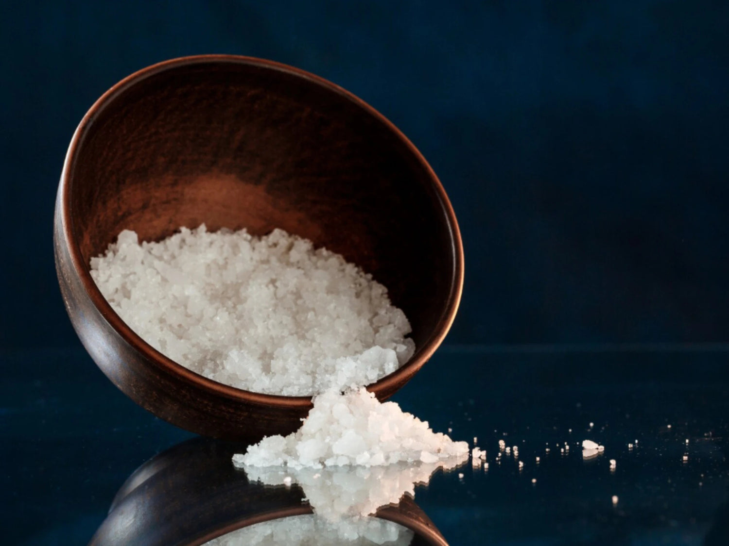 Cristaux blancs dans un bol, illustration du sodium PCACA, humectant qui aide à retenir l’eau dans la peau.