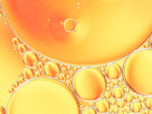 Bulles d’huile dorées en macro, illustration du tocopherol (vitamine E) utilisé en cosmétique comme antioxydant et pour aider à protéger les formules de l’oxydation.
