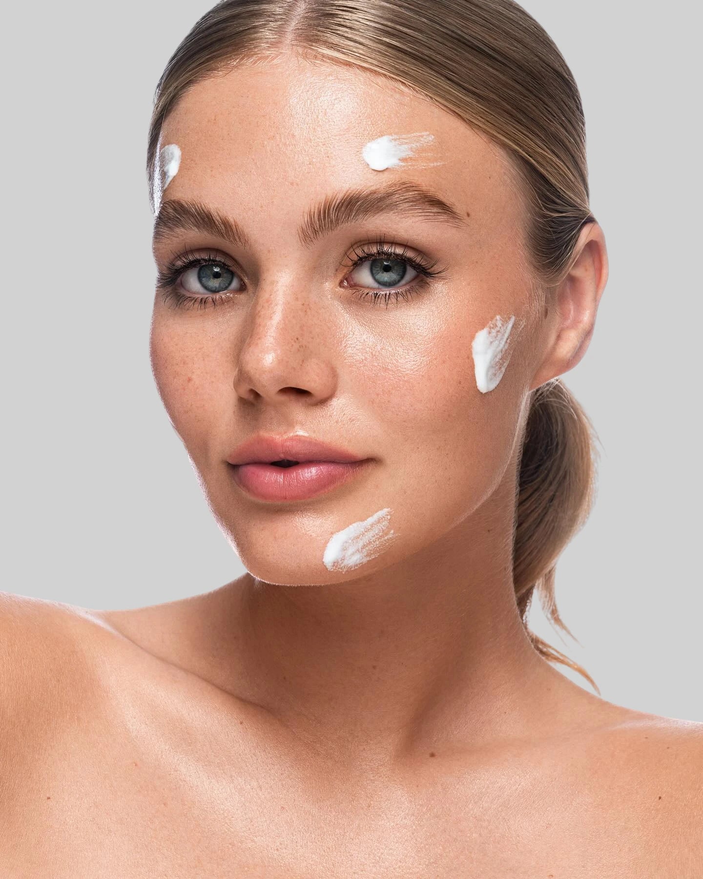 Application d’une crème hydratante sur le visage, texture crème, soin visage pour peau sensible.