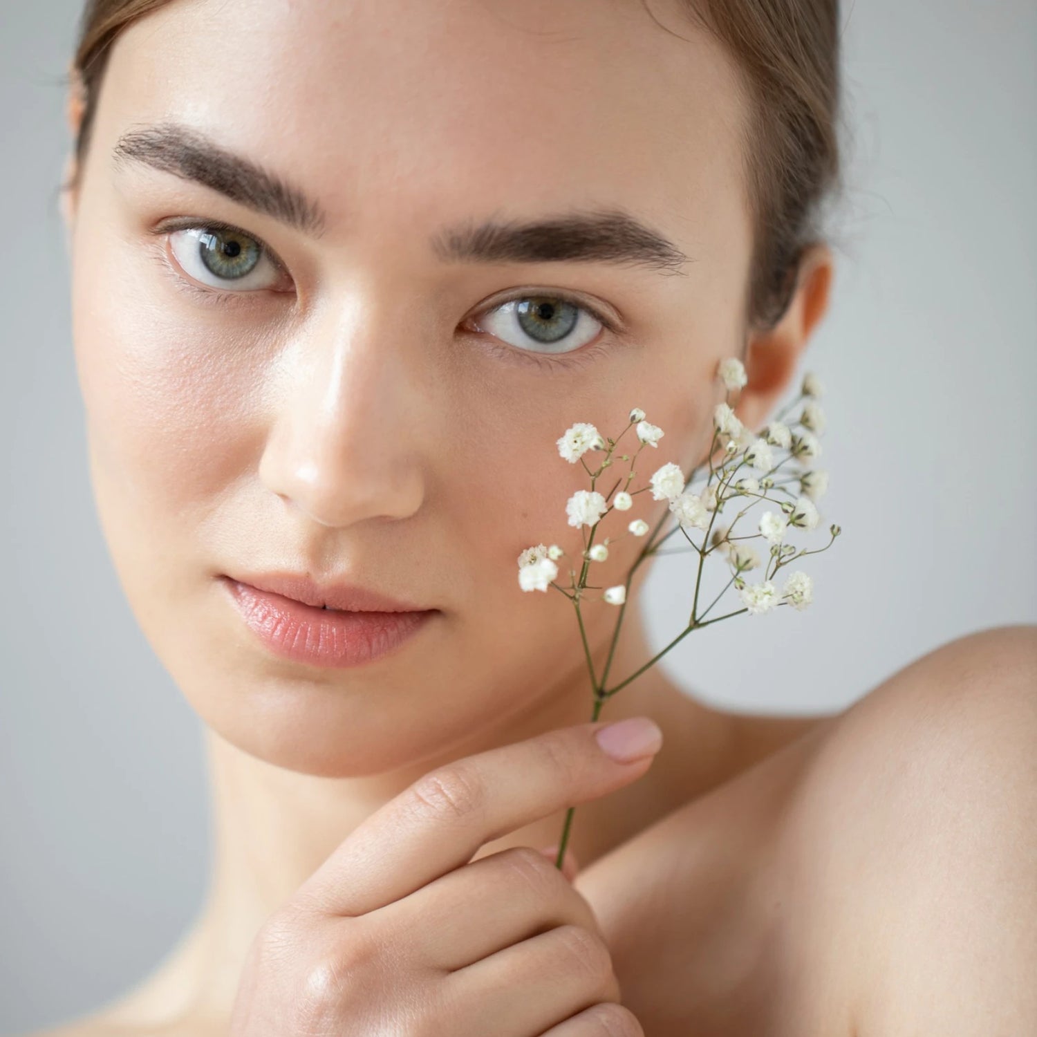 Portrait d’une femme tenant une fleur blanche, routine soin visage, peau sensible, univers cosmétique Seomse.