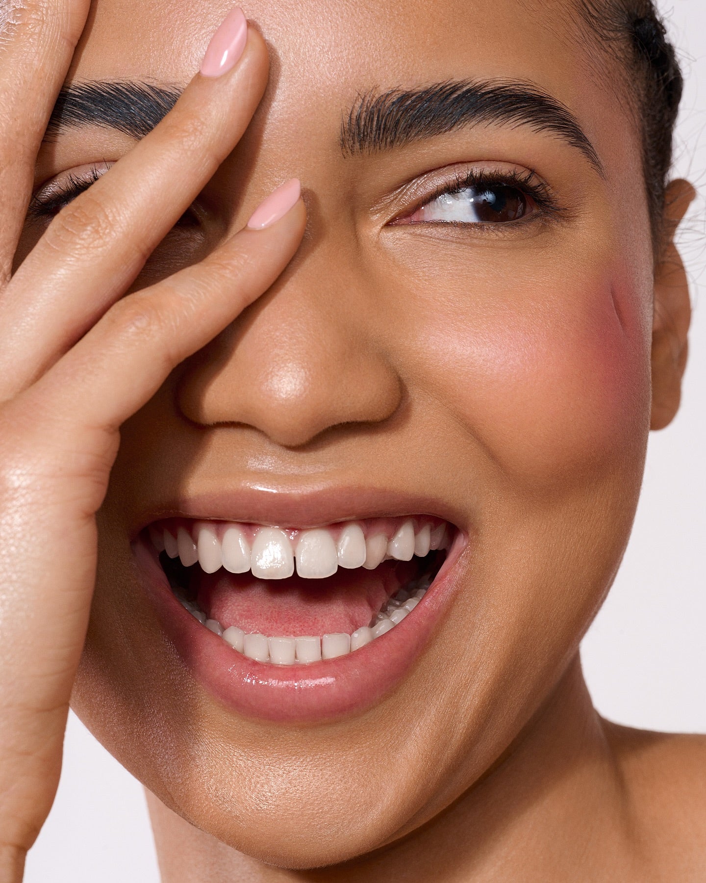 Visage d’une femme souriante, peau lumineuse, soin visage hydratant, routine avec crème hydratante.